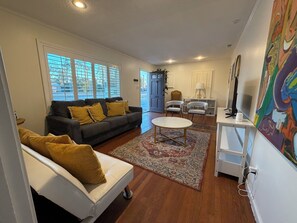 A living room with a sofa, chairs, a coffee table, and a painting on the wall. - Private 3BR Home • 4 Queen Beds + 3 Sofa Beds • Great Location (Valdosta)