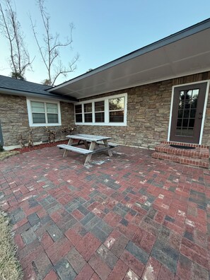 Ein Garten mit Steinmauer, Picknicktisch und gepflasterter Terrasse.