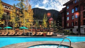 Ein Hotelpoolbereich mit Liegestühlen, einem Whirlpool und einem Blick auf die Berge.