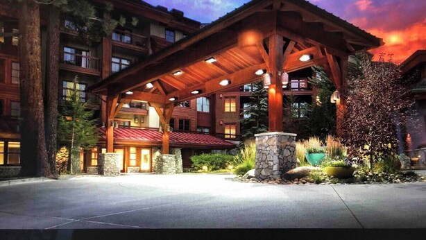 Eine Lodge mit überdachter Veranda, mehreren Balkonen und einer Steinfassade.