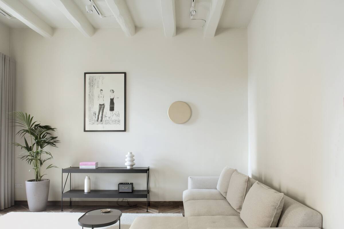 Una sala de estar moderna con un sofá seccional, una mesa de centro, una planta en maceta, una obra de arte enmarcada y un mueble consola minimalista.