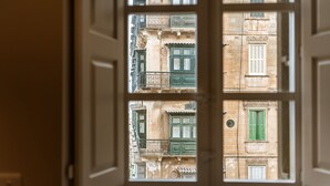 Une vue à travers une fenêtre à cadre blanc, dévoilant la façade d’un immeuble avec de nombreuses fenêtres et des balcons.