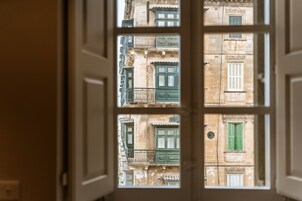 A view through a window with a white frame, revealing a building facade with multiple windows and balconies.