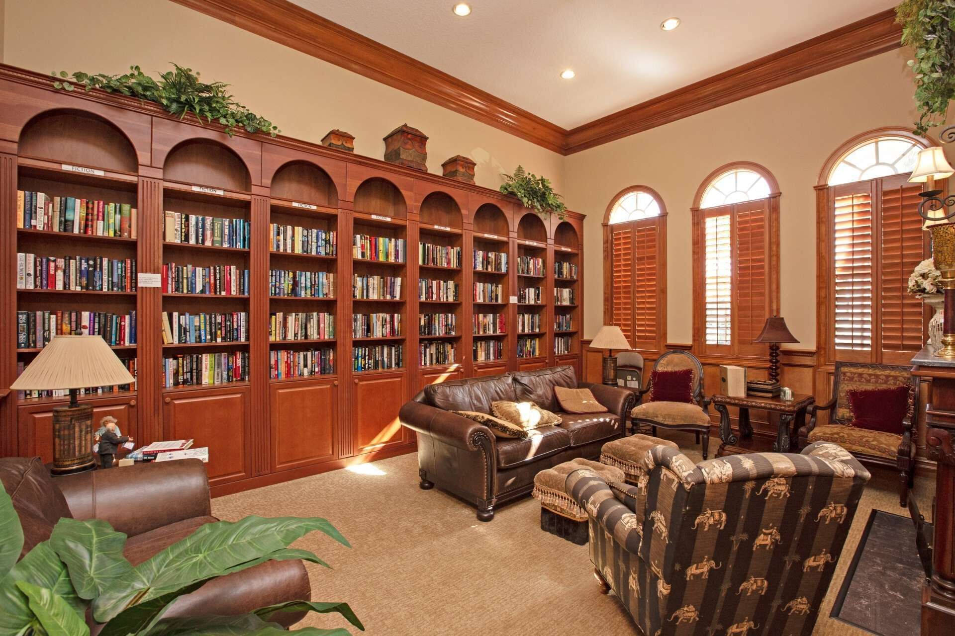A library with leather sofas, wooden bookshelves, and a fireplace.
