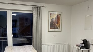 Una cocina moderna con una mesa de madera, un radiador y una máquina de café sobre un estante blanco.