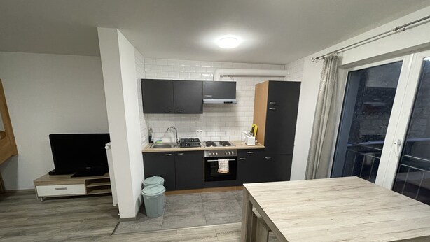 Una cocina compacta con comedor, televisor y balcón con vistas.