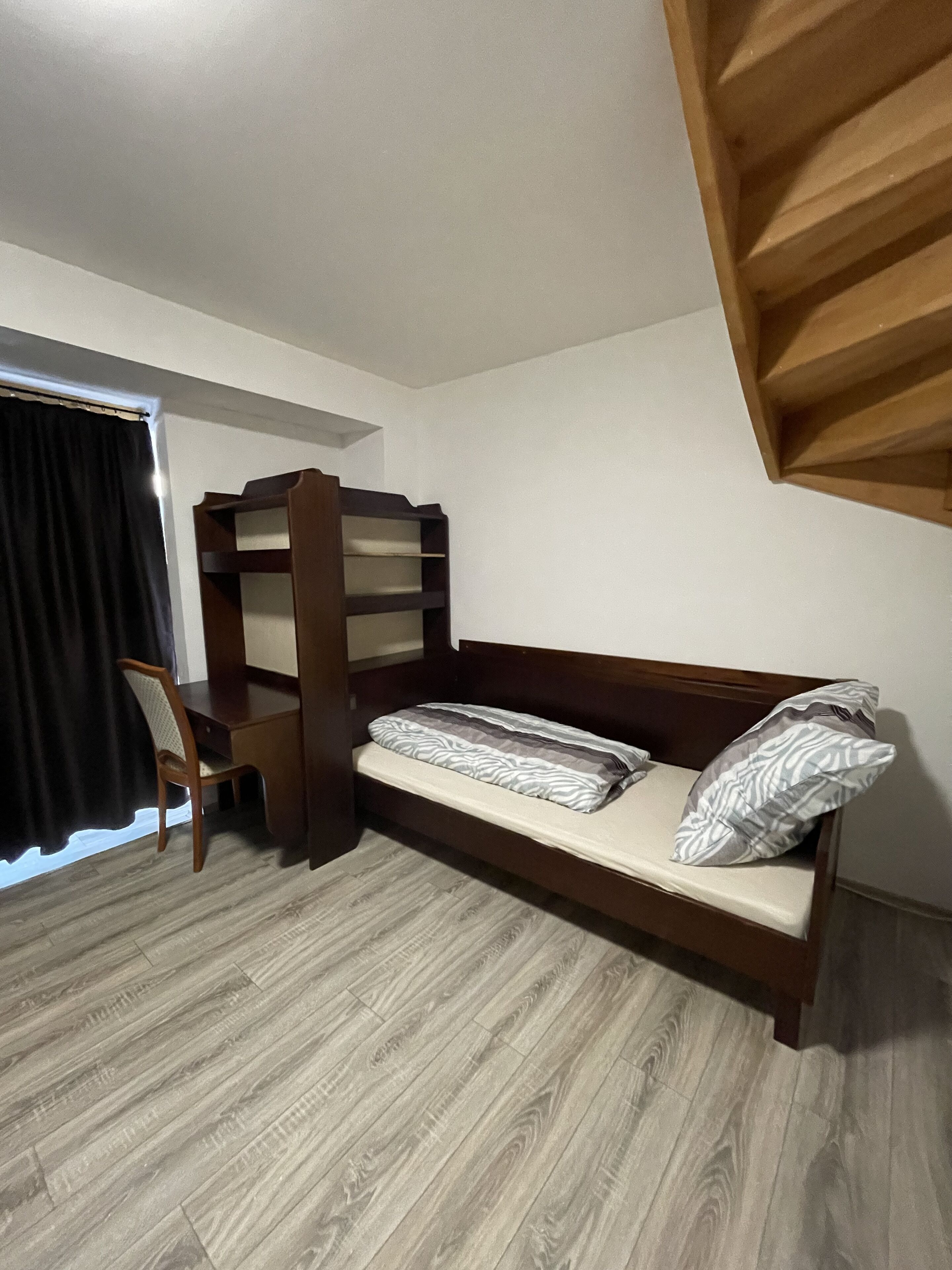 A dorm-style room with a bunk bed, a desk, and a chair.