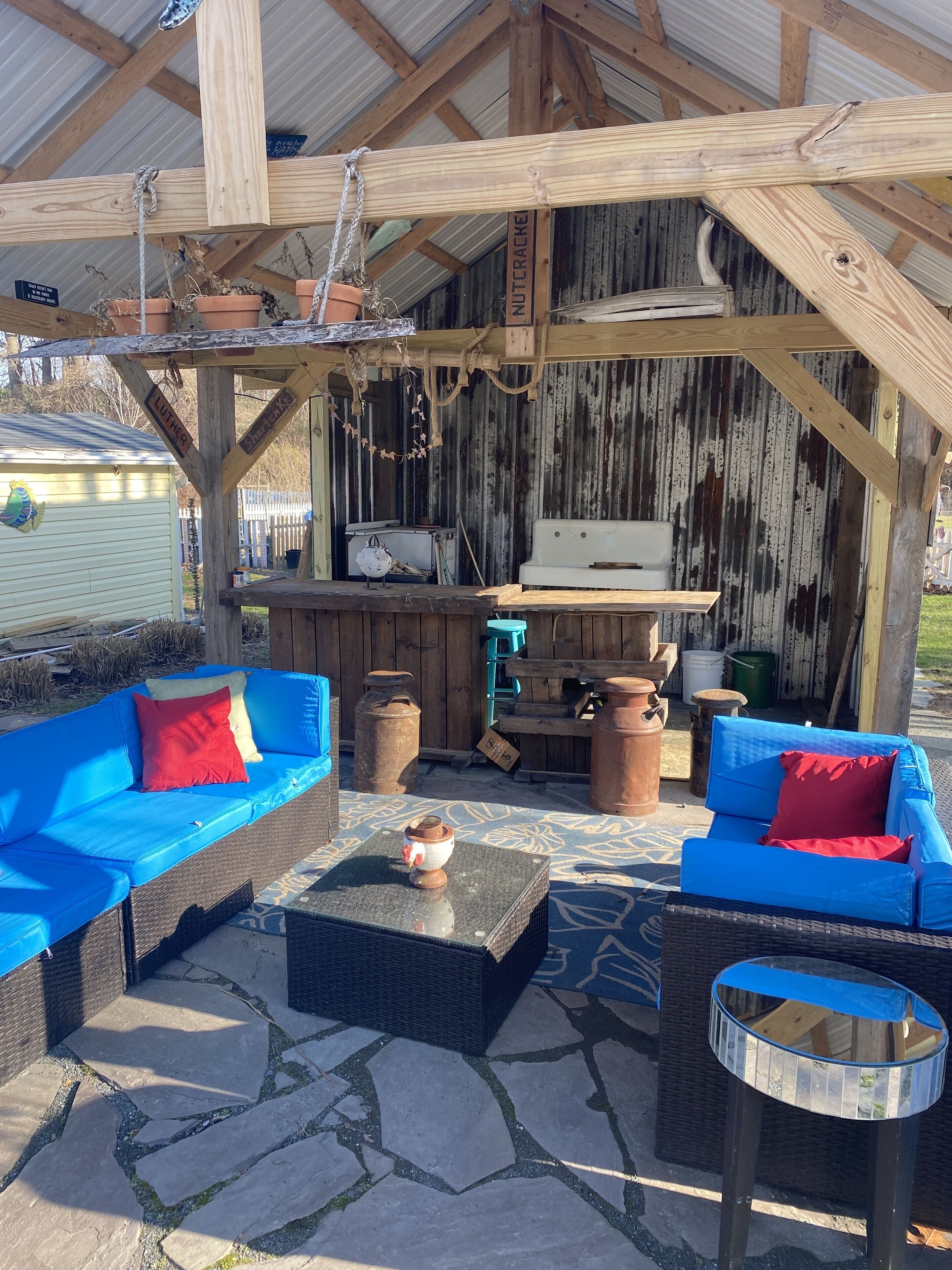 En udendørs patio med to blå sofaer, et lille bord med en pynteting og et rundt bord med blå bordplade.