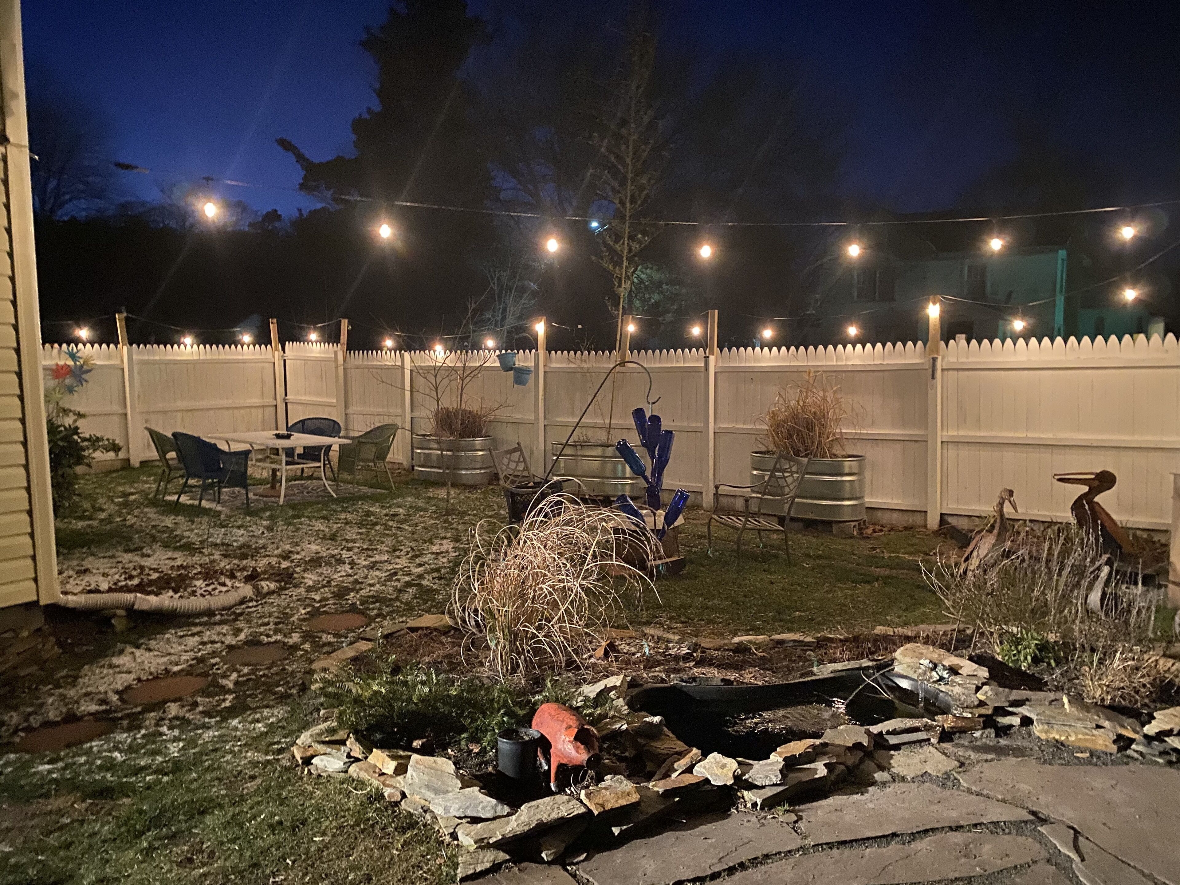 Ein Garten mit Terrasse, Sitzgelegenheiten und dekorativen Pflanzgefäßen.