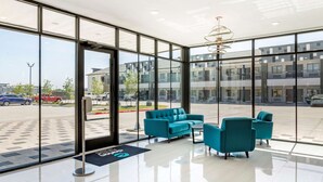 Un vestíbulo moderno con amplios ventanales, un mostrador de recepción y asientos color turquesa.