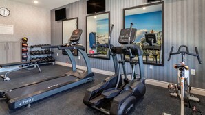 Un gimnasio con cintas de correr, elípticas y pesas.