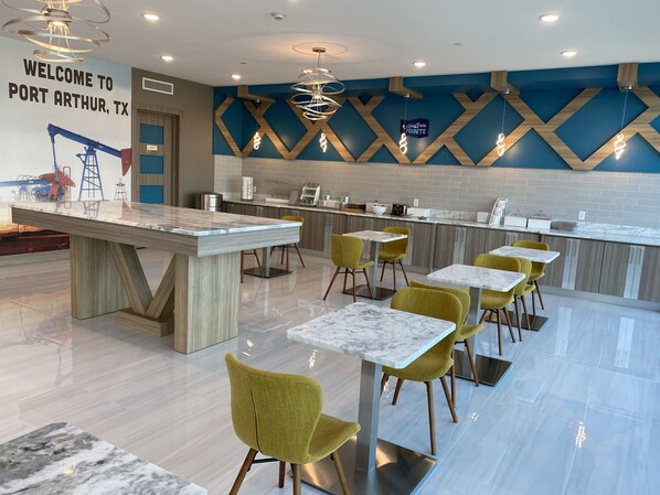 A modern restaurant with a bar area, yellow chairs, and a marble countertop. - Clarion Pointe Port Arthur-Beaumont South (Port Arthur)