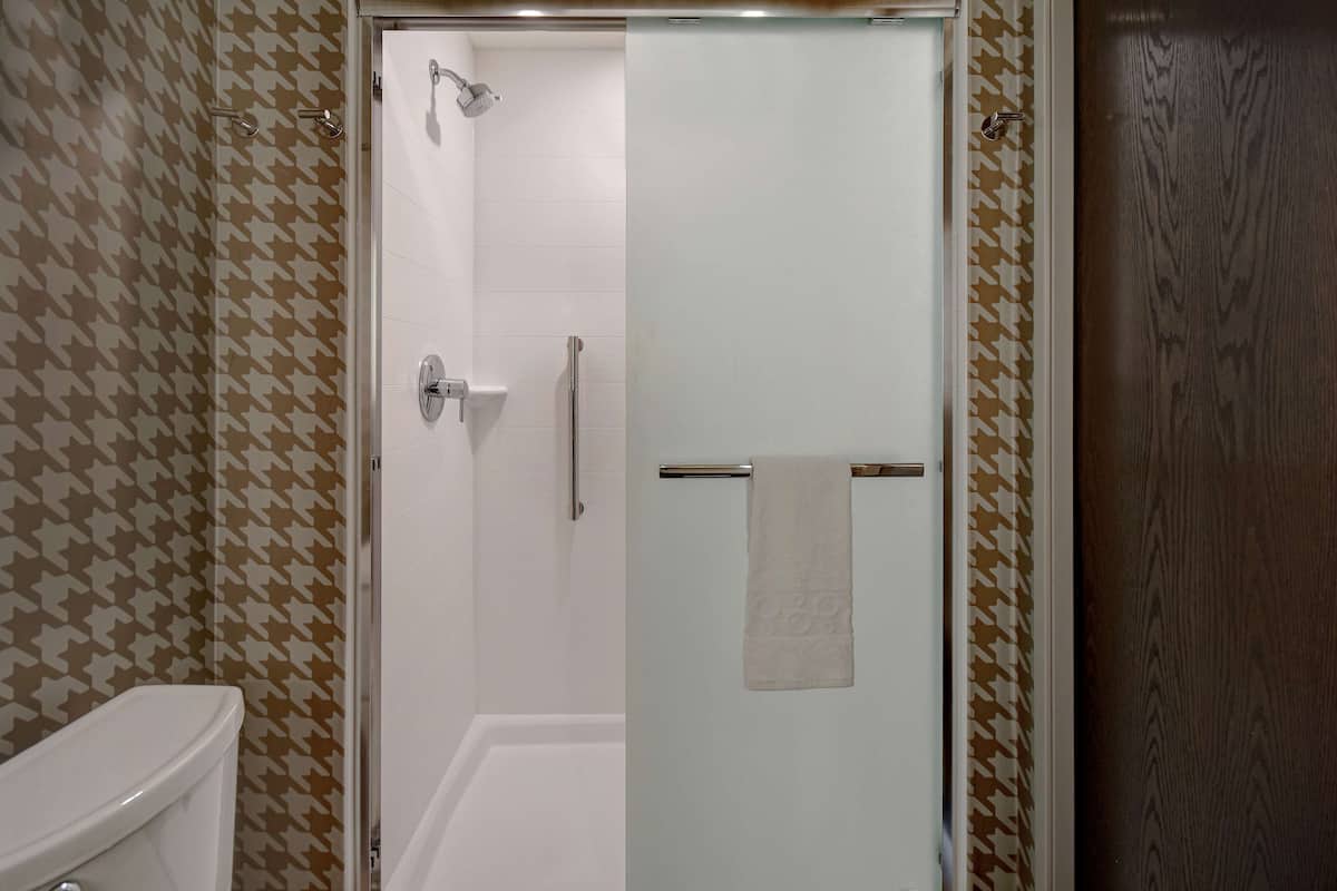 Un baño con mampara de vidrio, inodoro y paredes con diseño.