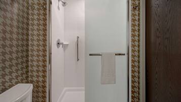 Une salle de bain avec une porte de douche en verre, des toilettes et des murs à motifs.