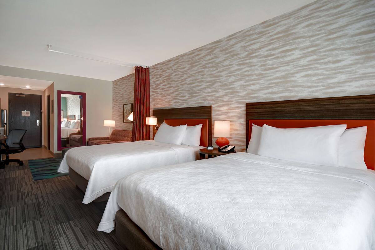 Habitación de hotel con dos camas, un escritorio y una silla.