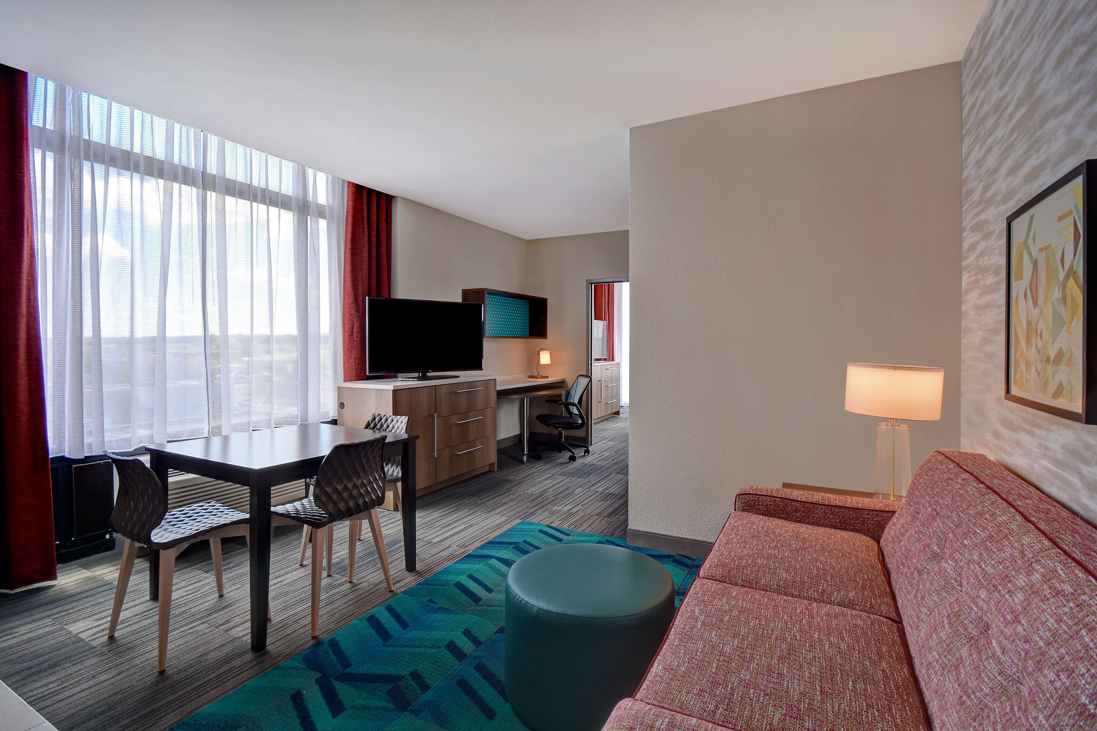 Habitación de hotel con comedor, sofá, televisión y escritorio.