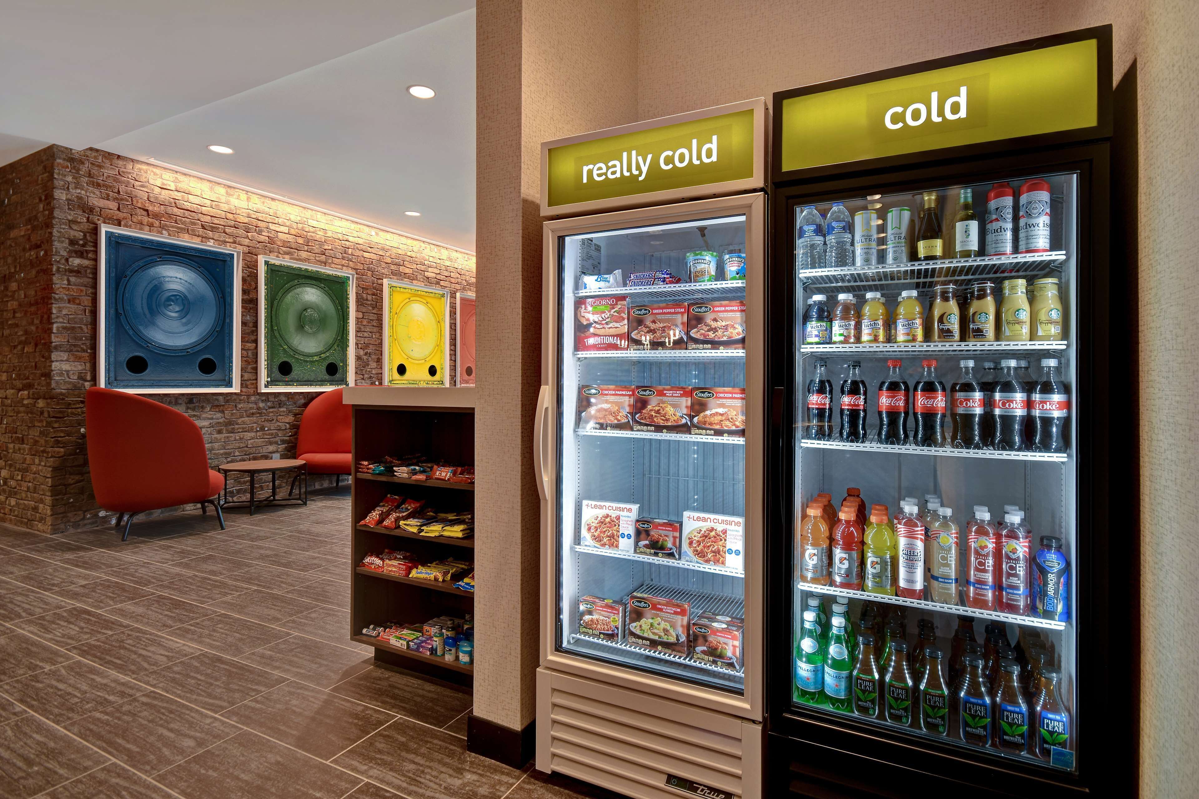 A hotel lobby with a seating area, a 'really cold' and a 'cold' beverage refrigerator, and a snack shelf.
