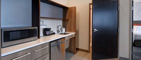 Une chambre d’hôtel compacte dotée d’une kitchenette, comprenant un four à micro-ondes, une machine à café et un évier.
