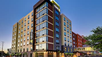 Un hotel de varios pisos con un llamativo letrero de "HOME 2", ventanas amplias y un diseño arquitectónico moderno.
