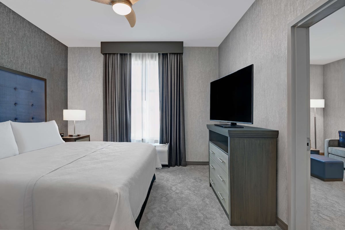 Une chambre d’hôtel avec un grand lit, un téléviseur à écran plat, une commode et un ventilateur de plafond.