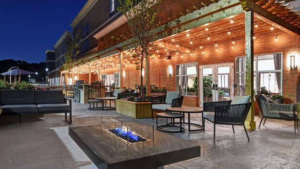Un espace extérieur aménagé avec une terrasse, un foyer et des guirlandes lumineuses.