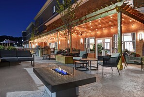 Un espace extérieur aménagé avec une terrasse, un foyer et des guirlandes lumineuses.