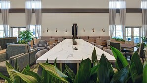 Une salle de conférence spacieuse, dotée d’une grande table en marbre, de sièges confortables et de larges fenêtres équipées de rideaux.