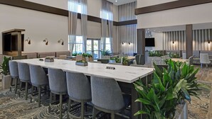 Une salle de conférence spacieuse, dotée d’une longue table, de nombreuses chaises et d’un ventilateur de plafond moderne.