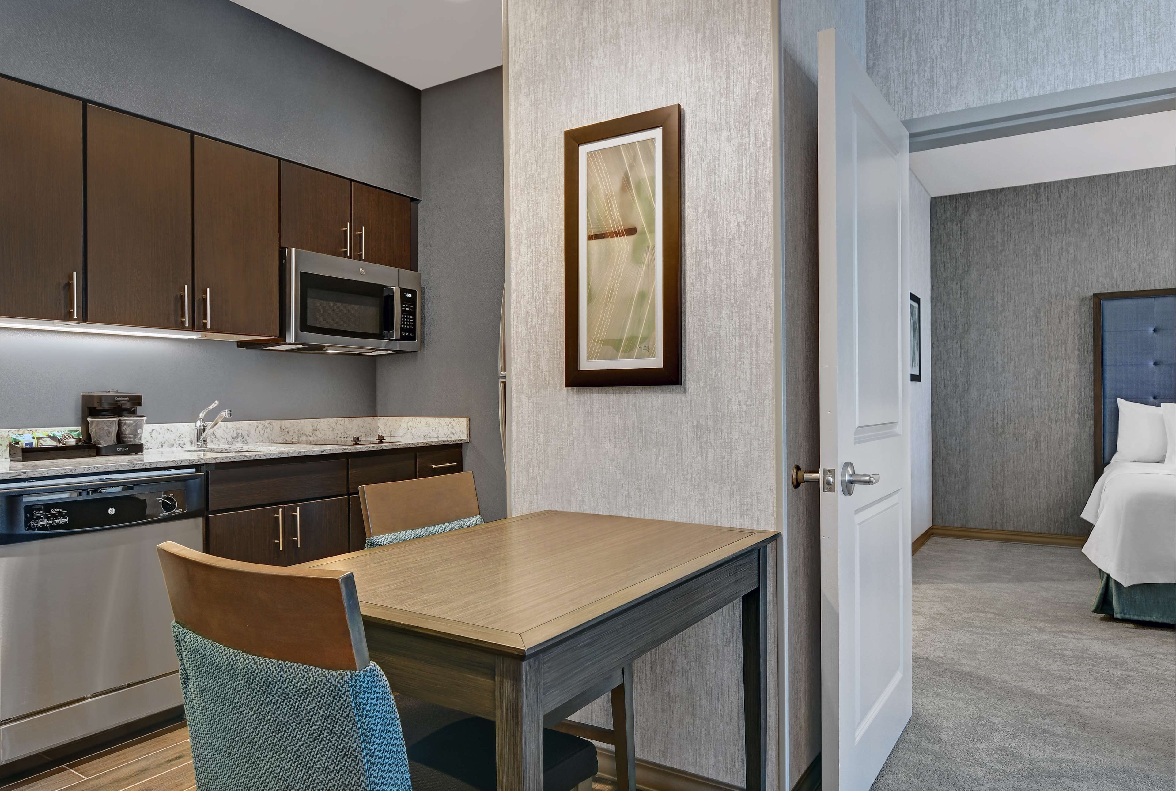 Una habitación de hotel compacta con kitchenette, comedor y cama.