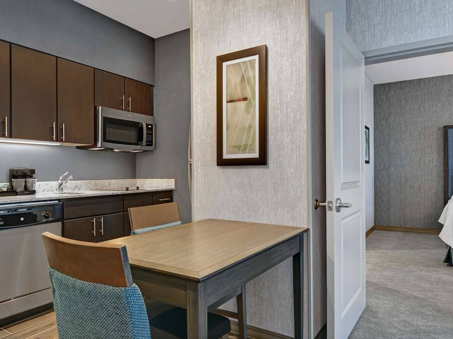 Una habitación de hotel compacta con kitchenette, comedor y cama.