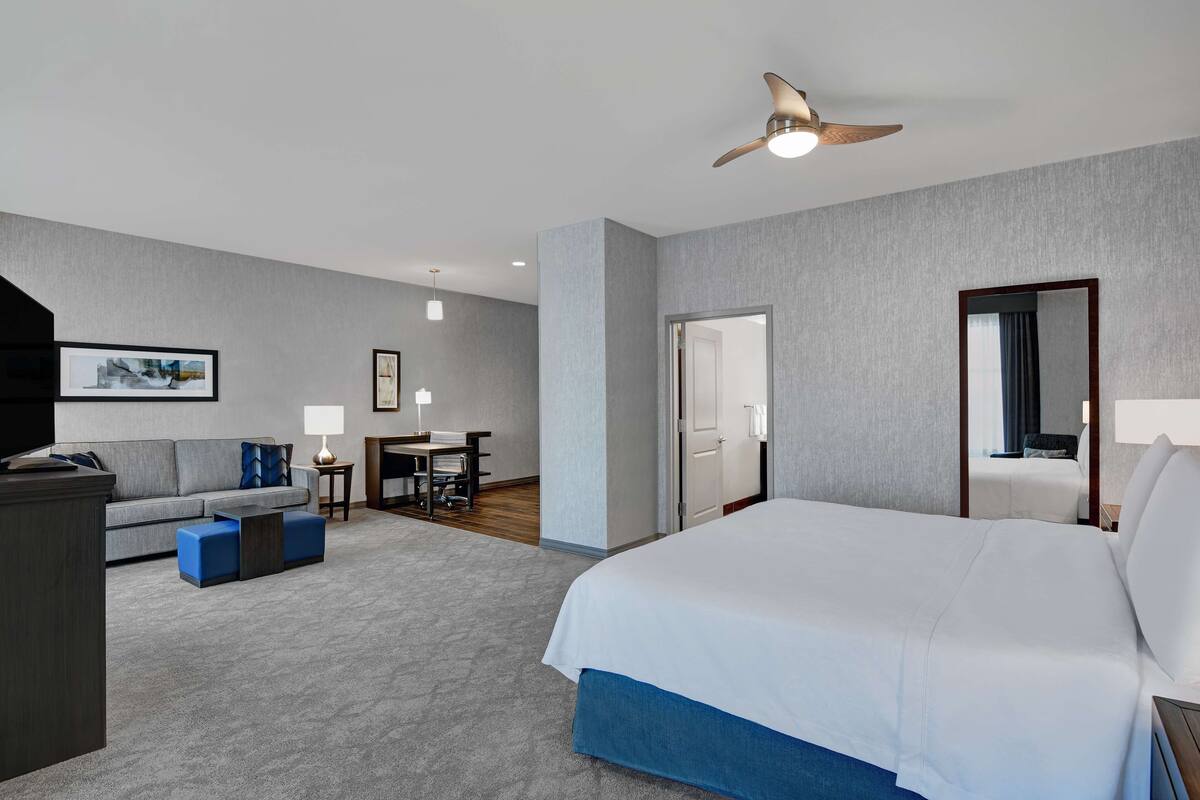 Une chambre d’hôtel avec un grand lit, un bureau, un canapé et un ventilateur de plafond.