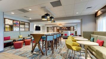 A modern lounge area with a bar, seating, and a patterned carpet.