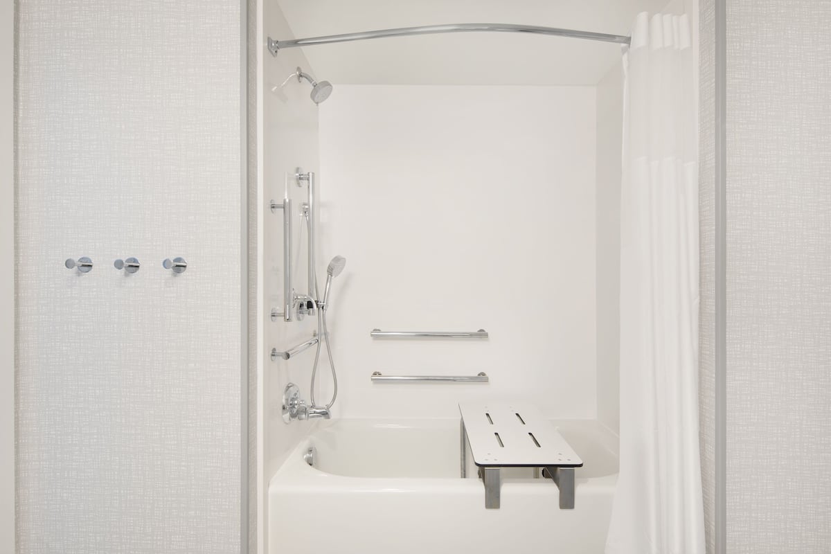 Ein modernes Badezimmer mit Badewanne, Dusche und zwei Handtuchhaltern.