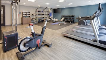 A gym with treadmills, stationary bikes, and free weights.