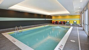 Piscina interior con carriles claramente delimitados, zona de vestuarios con asientos y vistas al exterior a través de amplios ventanales.