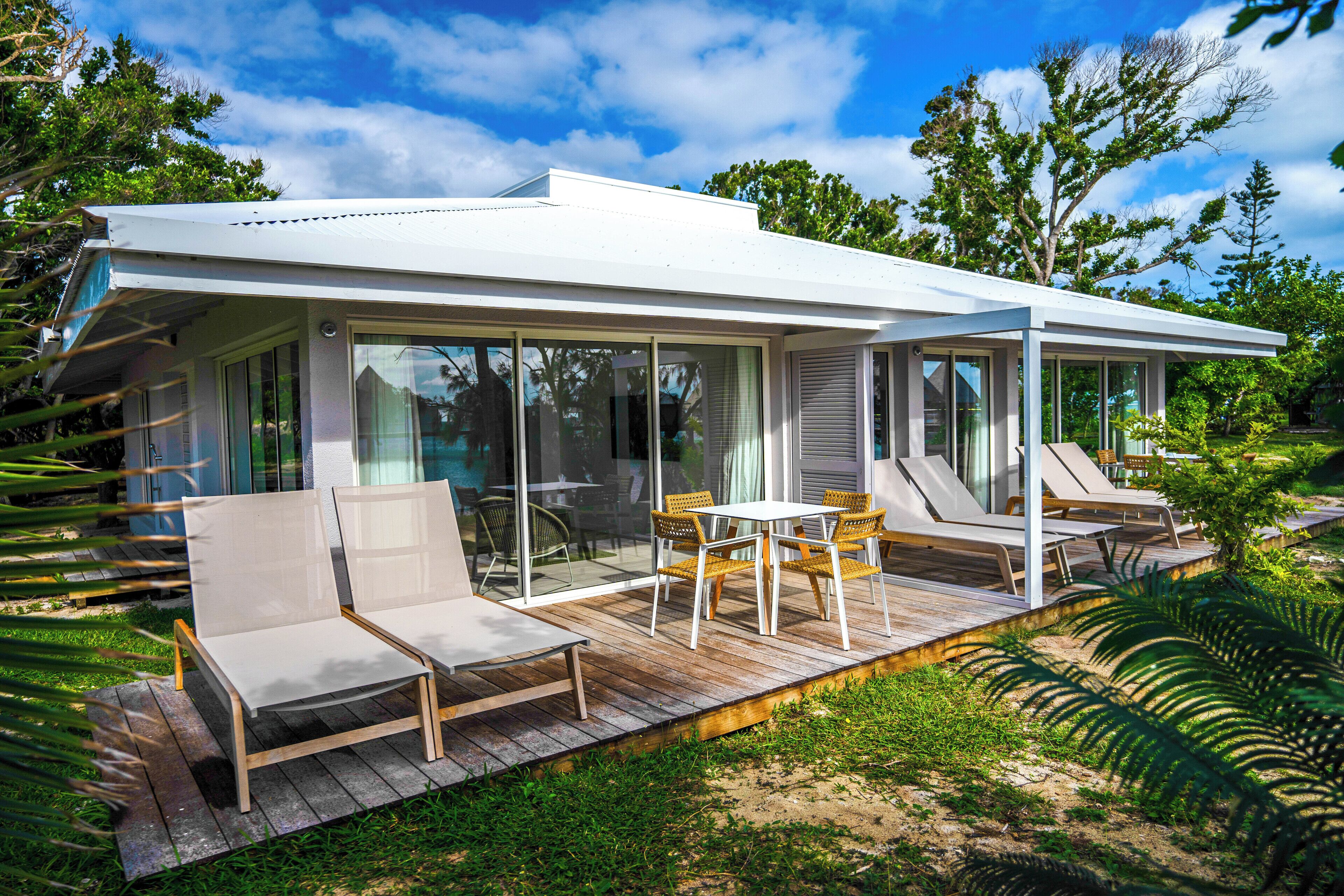 Een modern huis met een overdekte patio, glazen deuren en tuinmeubilair.