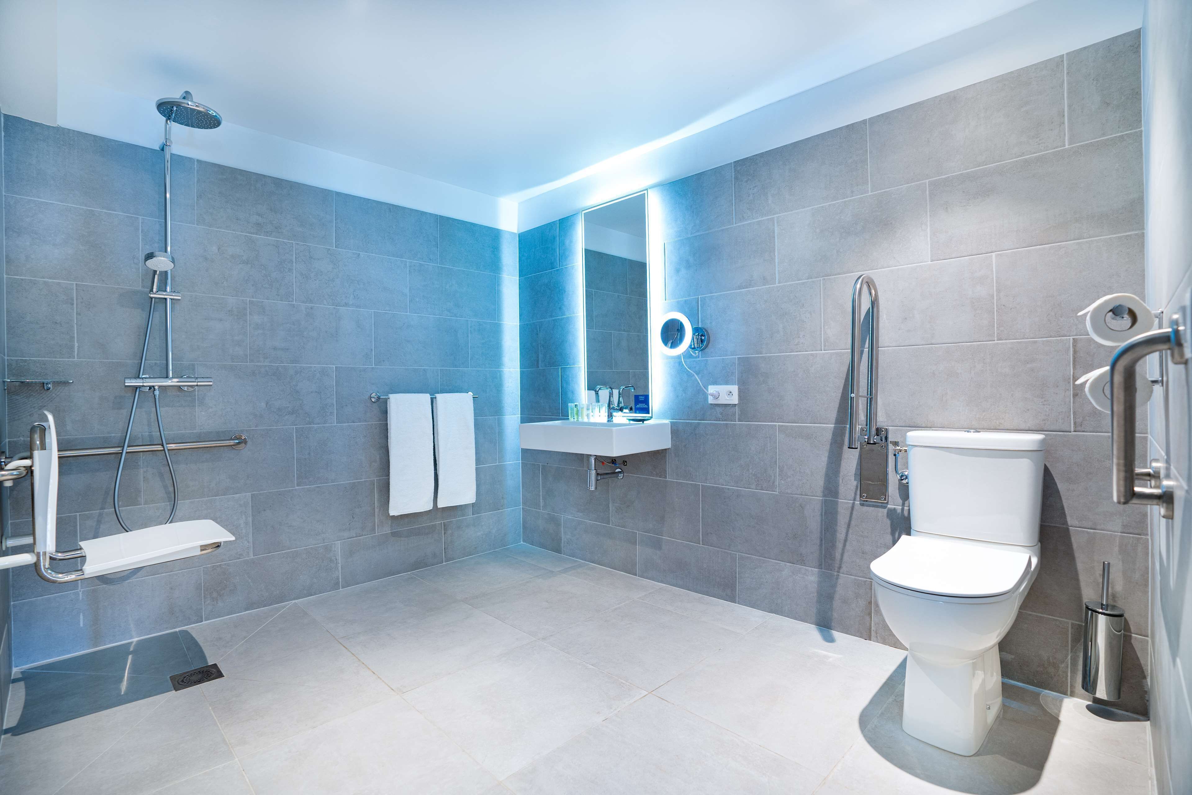 Une salle de bain moderne équipée d’une douche, de toilettes, d’un lavabo et d’un miroir de coiffeuse.