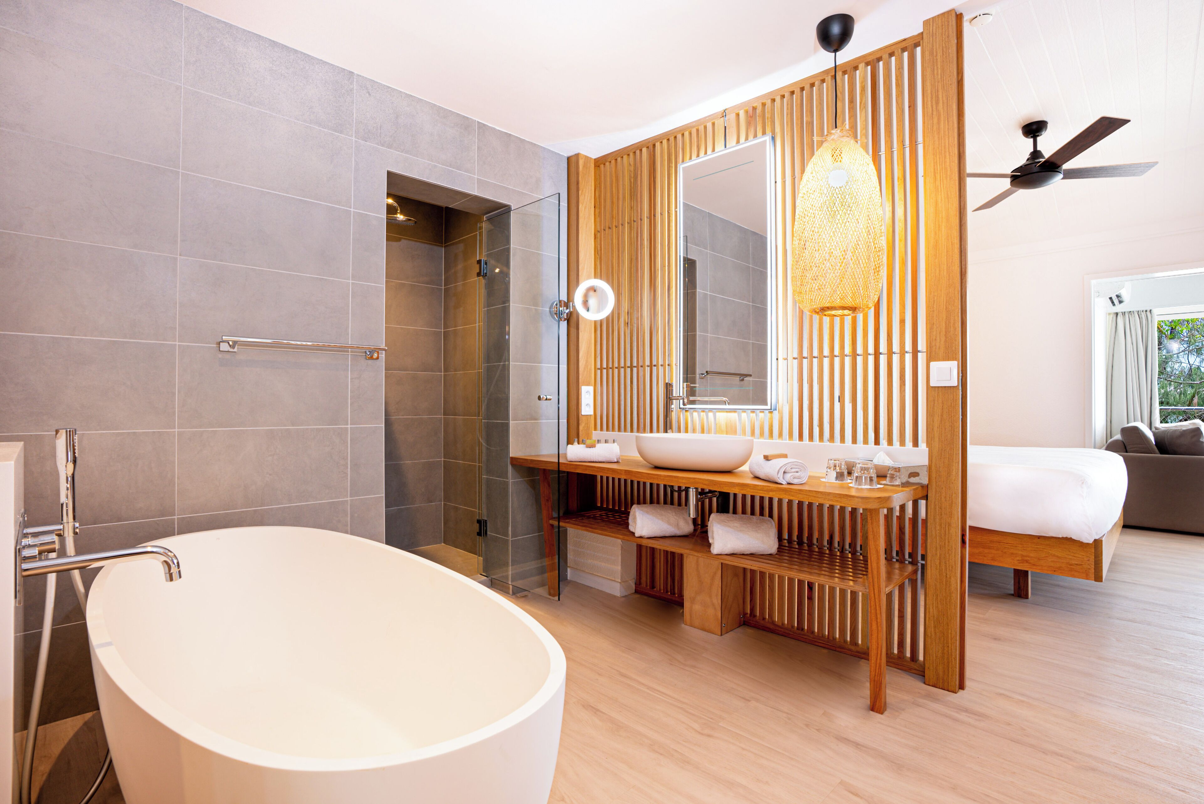 A modern bathroom with a freestanding bathtub, a glass-enclosed shower, and a wooden vanity with a large mirror.