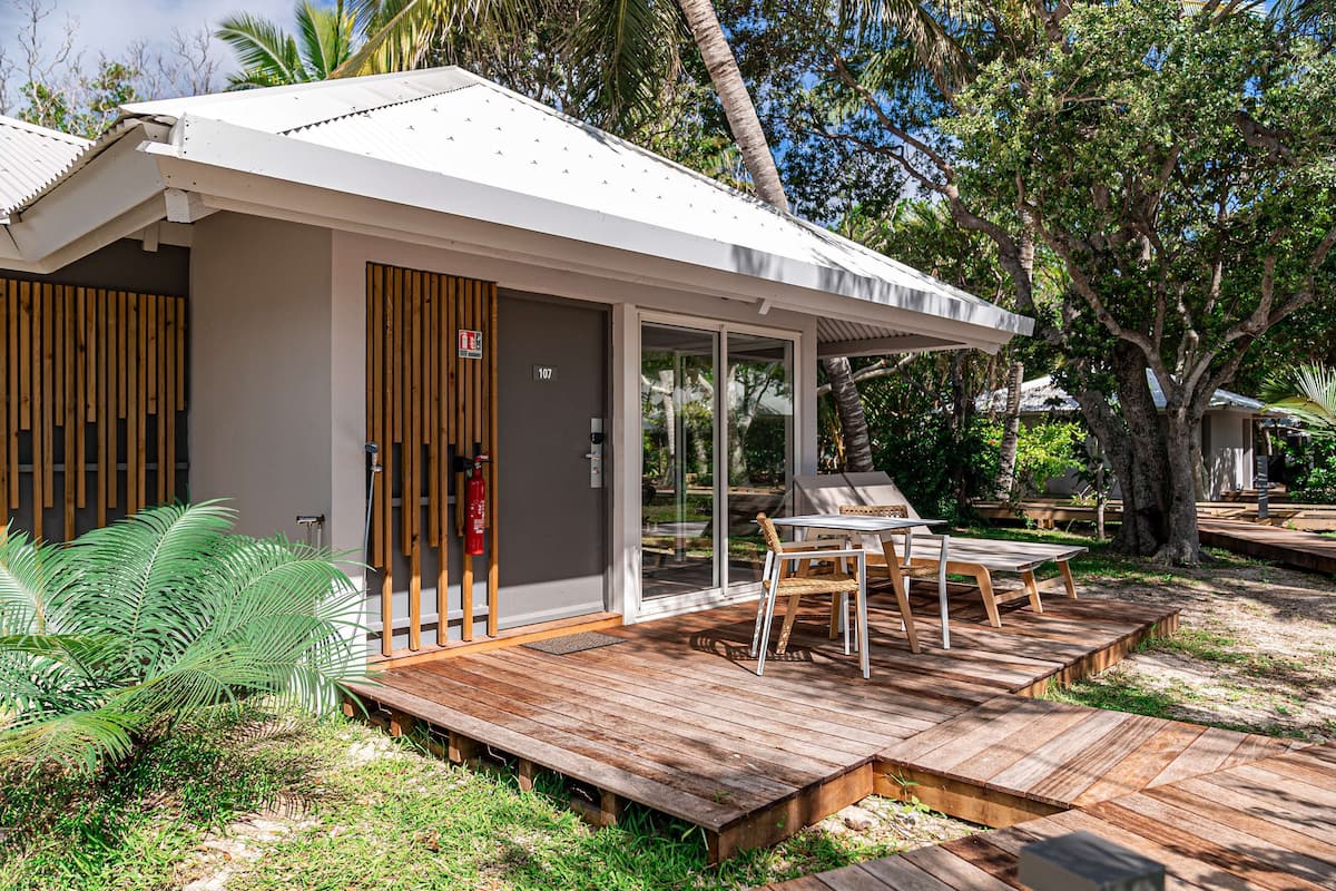 A modern house with a wooden deck, a glass door, and a number 107 sign.