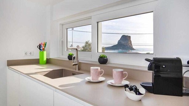 A modern kitchen with a large window, a sink, and a coffee machine.
