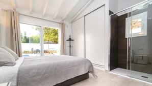 A bedroom with a bed, a sliding door closet, and a glass shower enclosure.