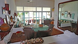 A spacious room with a large window, a round table with chairs, a sofa, and a mirror.