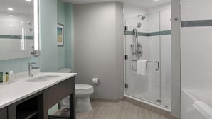 Uma casa de banho moderna com chuveiro em cabine de vidro, toucador com espelho e sanita.