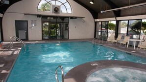 An indoor swimming pool with a hot tub, glass doors, and lounge chairs. - Pelican Pointe 504 by Liquid Life (Orange Beach)