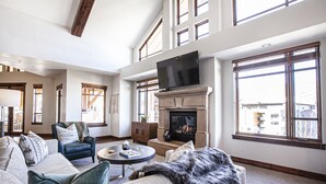A spacious living room with a fireplace, large windows, a television, and comfortable seating. - Hyatt at the Canyons by Park City Vacations (Park City)
