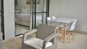 A modern room with a glass door leading to a balcony, a white table with chairs, and wicker furniture. - Apartamento Vacacional San Andres (San Andrés)