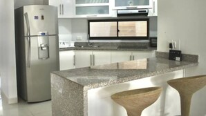 A modern kitchen with stainless steel appliances, white cabinets, and a granite countertop. - Apartamento Vacacional San Andres (San Andrés)