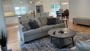 A modern living room with a grey sofa, a round coffee table, and a patterned rug.