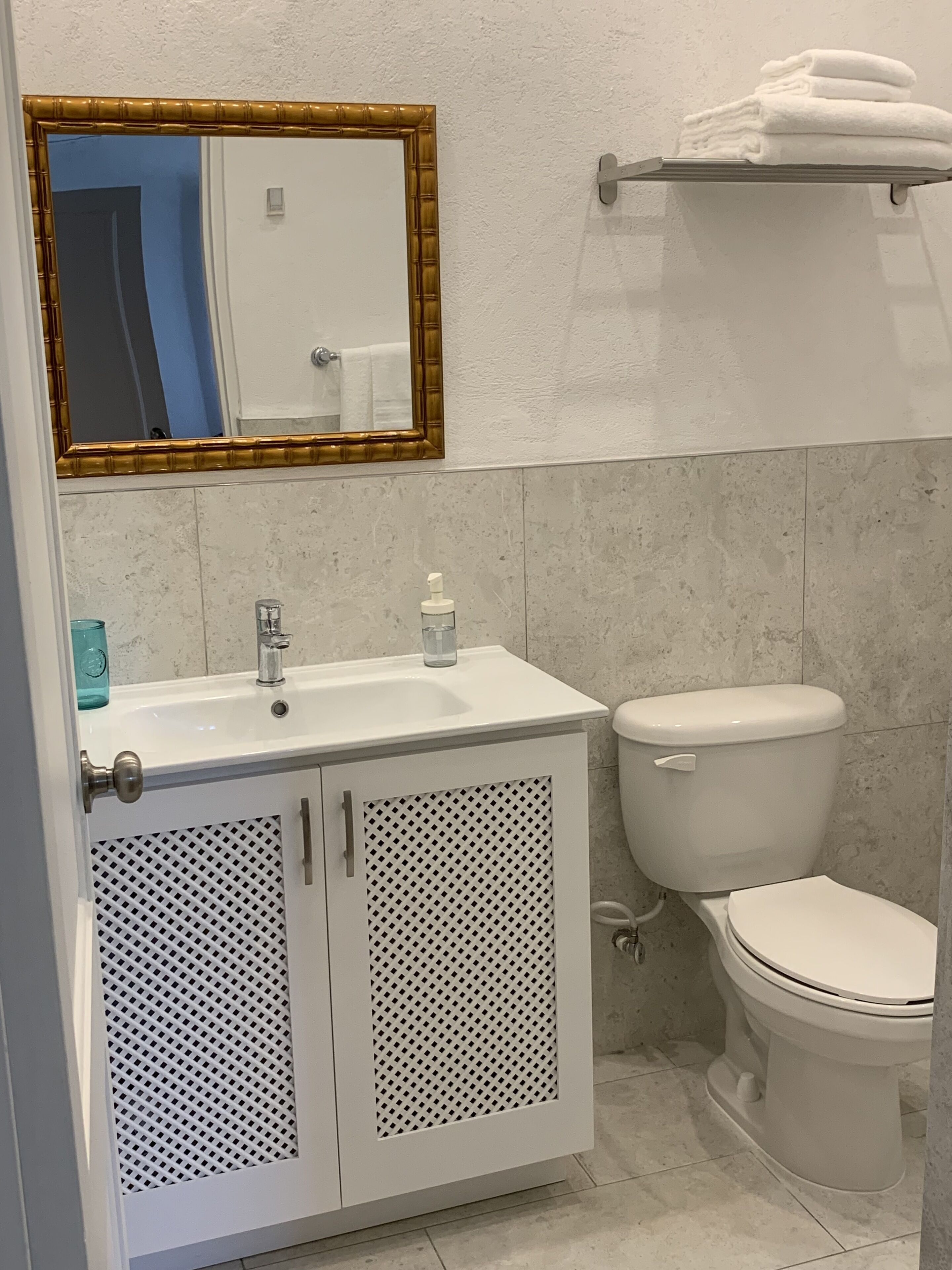 Un baño con un lavamanos blanco, un inodoro y un espejo con marco dorado.