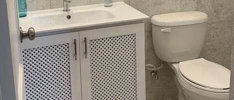 Un baño con un lavamanos blanco, un inodoro y un espejo con marco dorado.